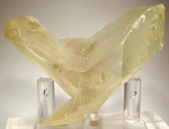 A pale gypsum swallowtail twin: two monoclinic blades joined along a plane so the pair opens like a V.